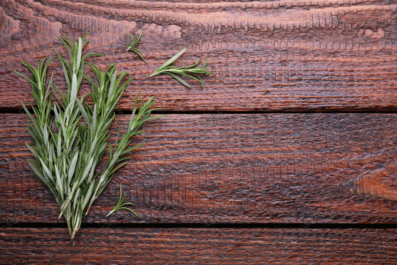 Photo of Fresh green rosemary twigs on wooden table, top view. Space for text