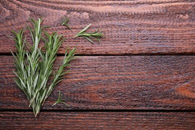 Photo of Fresh green rosemary twigs on wooden table, top view. Space for text