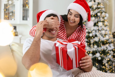 Photo of Young woman presenting Christmas gift to her boyfriend at home
