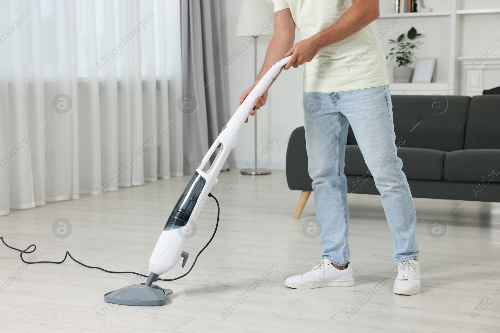 Photo of Man cleaning floor with steam mop at home, closeup