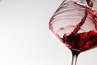 Tasty red wine in glass on white background, closeup. Space for text