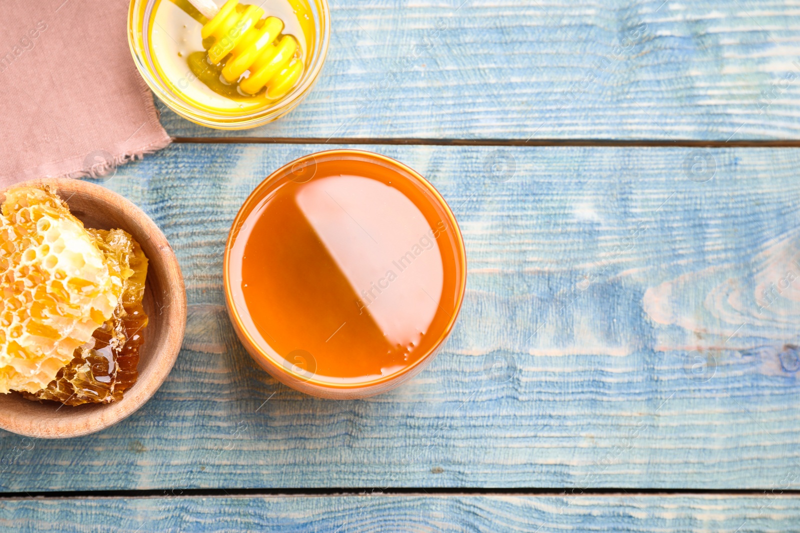 Photo of Tasty honey on light blue wooden table, flat lay. Space for text