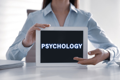 Psychologist with modern tablet at white table in office, closeup 