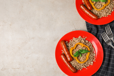 Photo of Tasty buckwheat porridge with sausages on light table, flat lay. Space for text