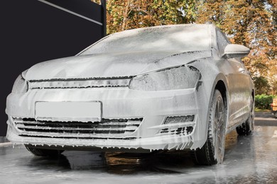 Auto with cleaning foam at outdoor car wash