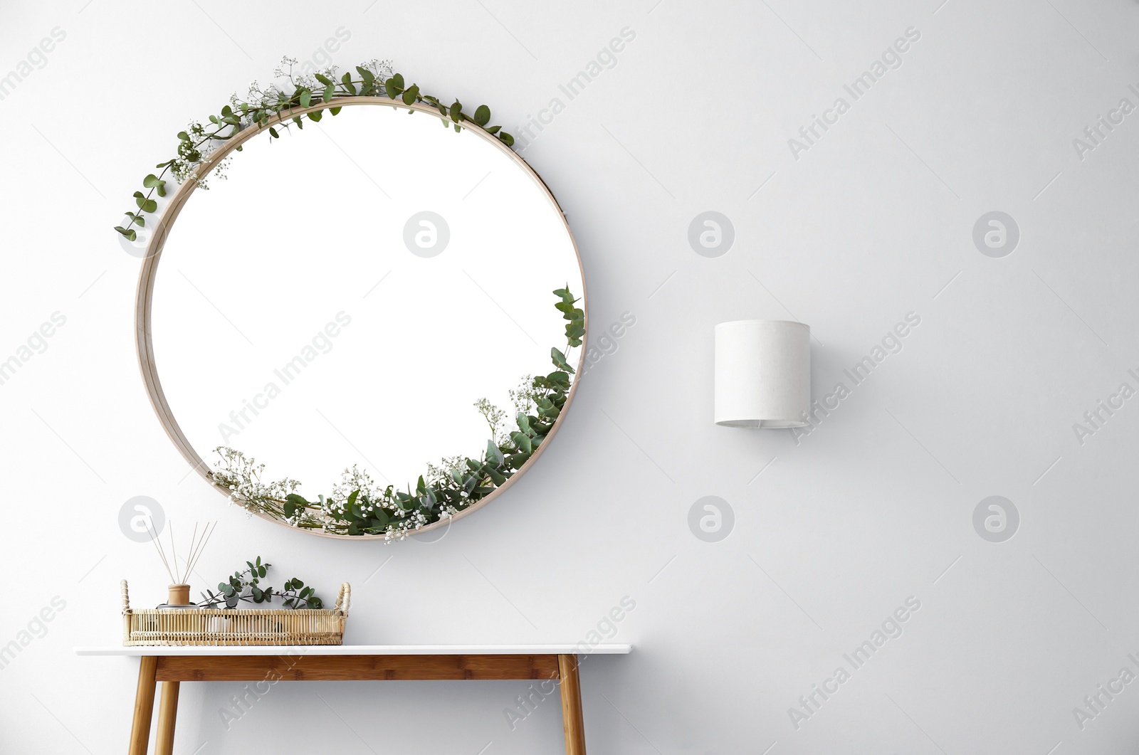 Photo of Round mirror and table with accessories near white wall in modern room interior