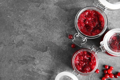 Photo of Jars with tasty cranberry sauce on grey background, flat lay. Space for text