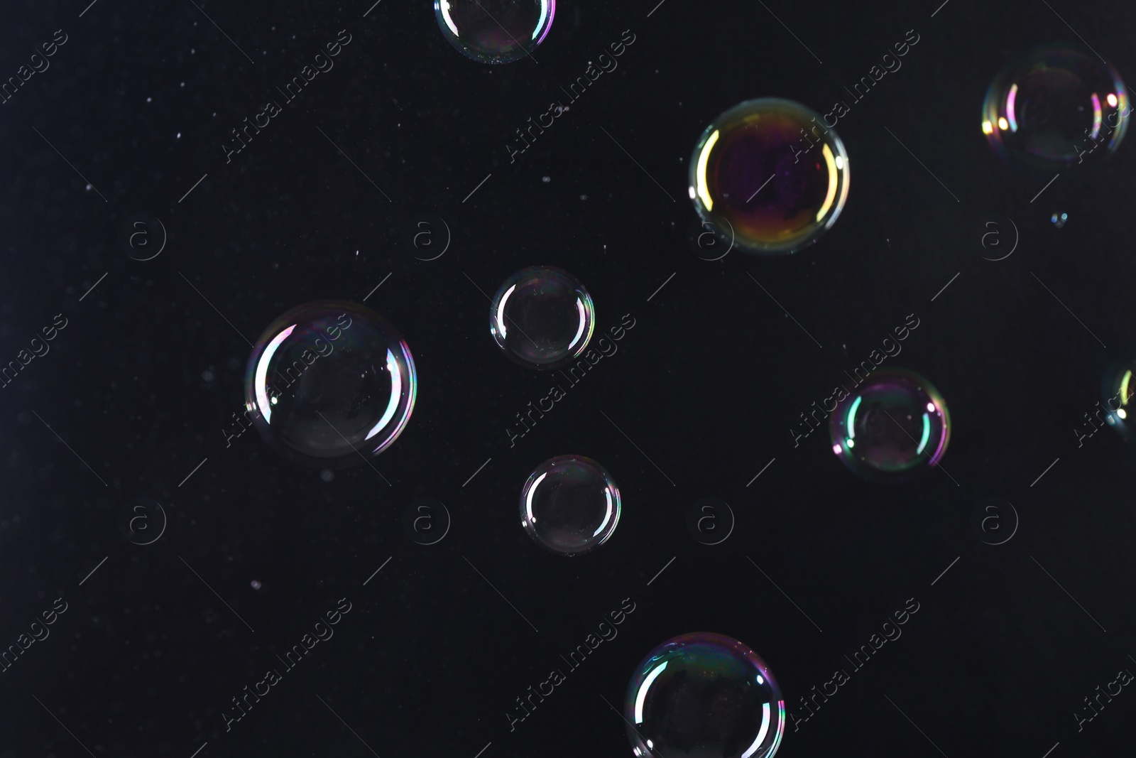 Photo of Beautiful transparent soap bubbles on dark background