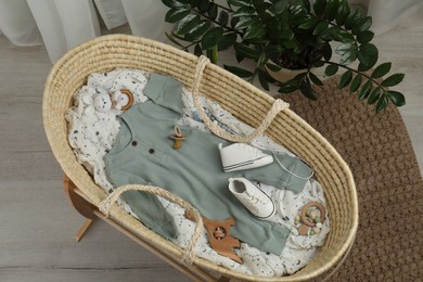 Photo of Cute baby clothes and accessories in basket bassinet at home, top view