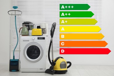 Energy efficiency rating label and different household appliances near window indoors