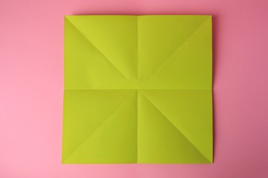 Photo of Origami art. Sheet of color paper on pink background, top view
