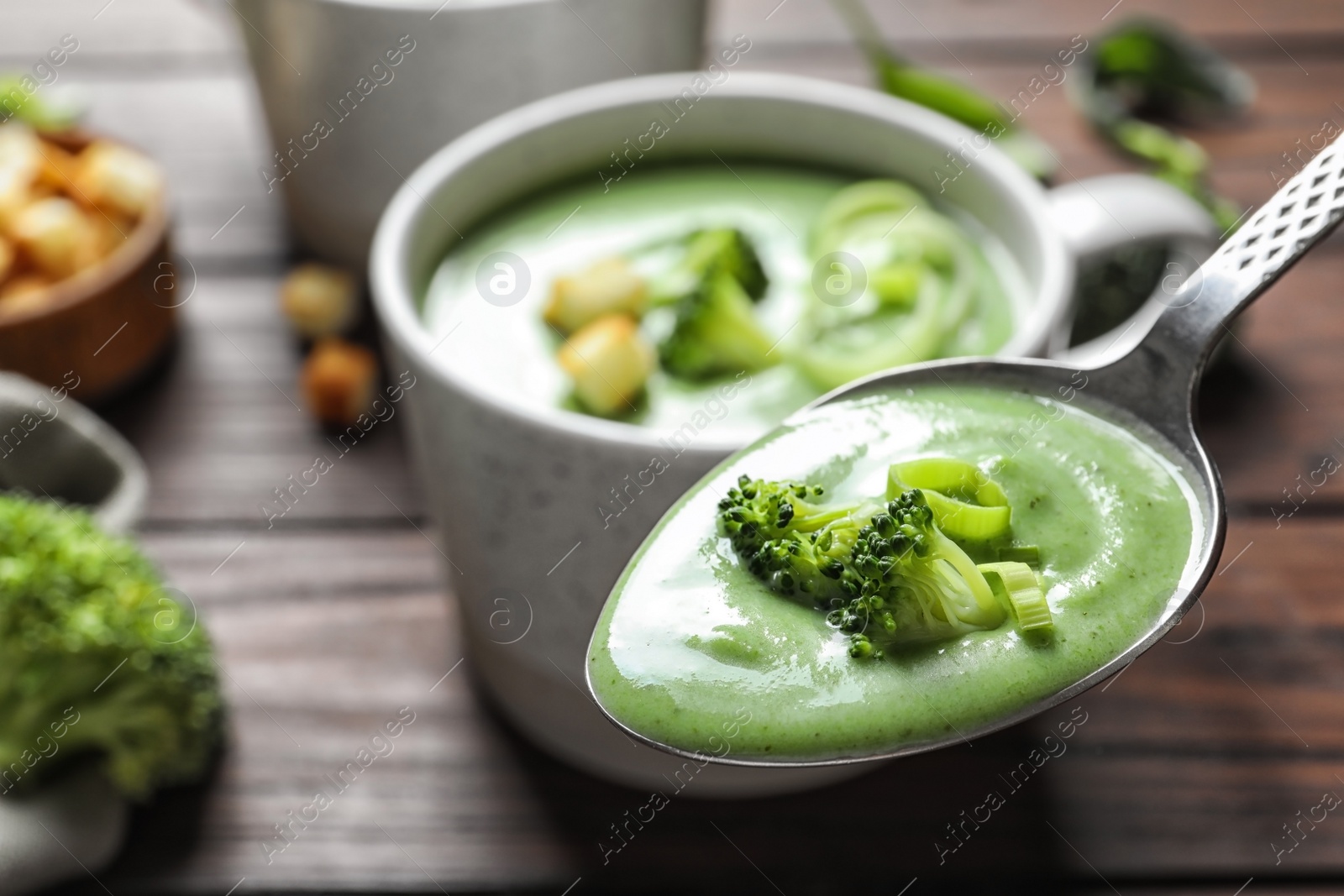 Photo of Spoon with fresh vegetable detox soup made of broccoli on blurred background, closeup