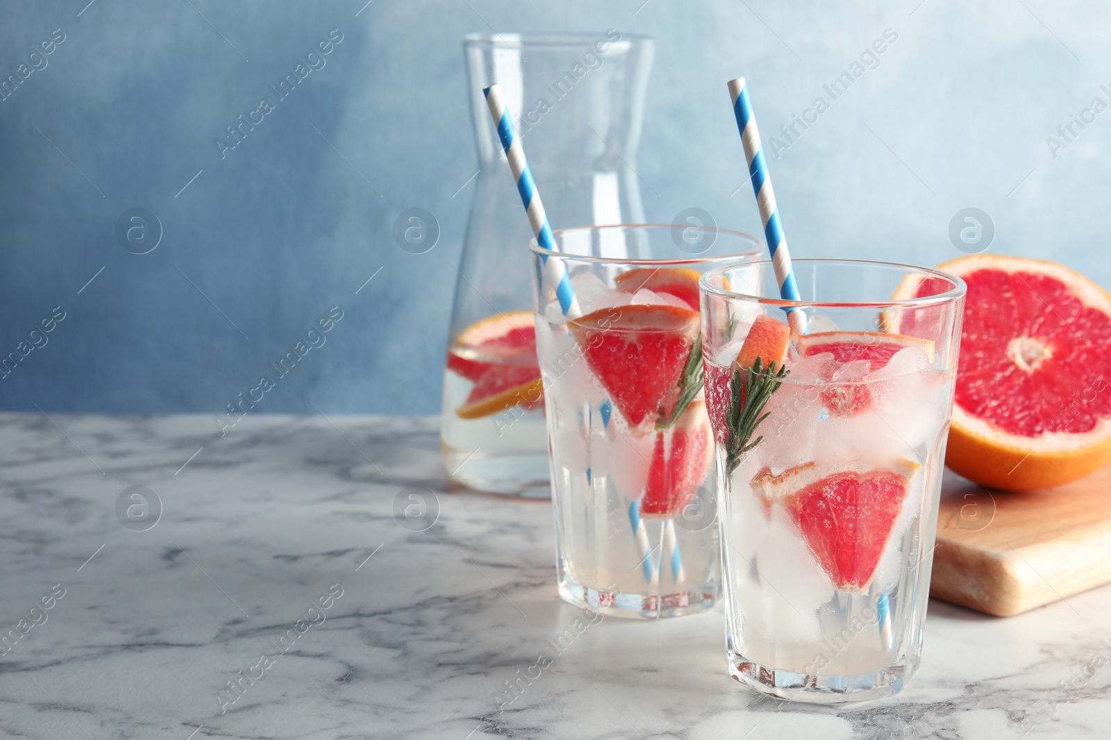 Photo of Glasses of infused water with grapefruit slices on table. Space for text