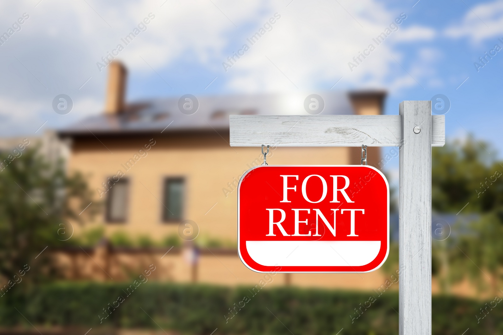 Image of Sign with phrase FOR RENT and blurred view of beautiful house