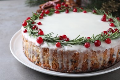 Photo of Traditional Christmas cake decorated with rosemary and cranberries on light grey table, closeup