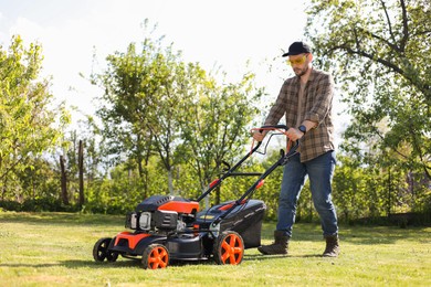 Photo of Man cutting green grass with lawn mower in garden