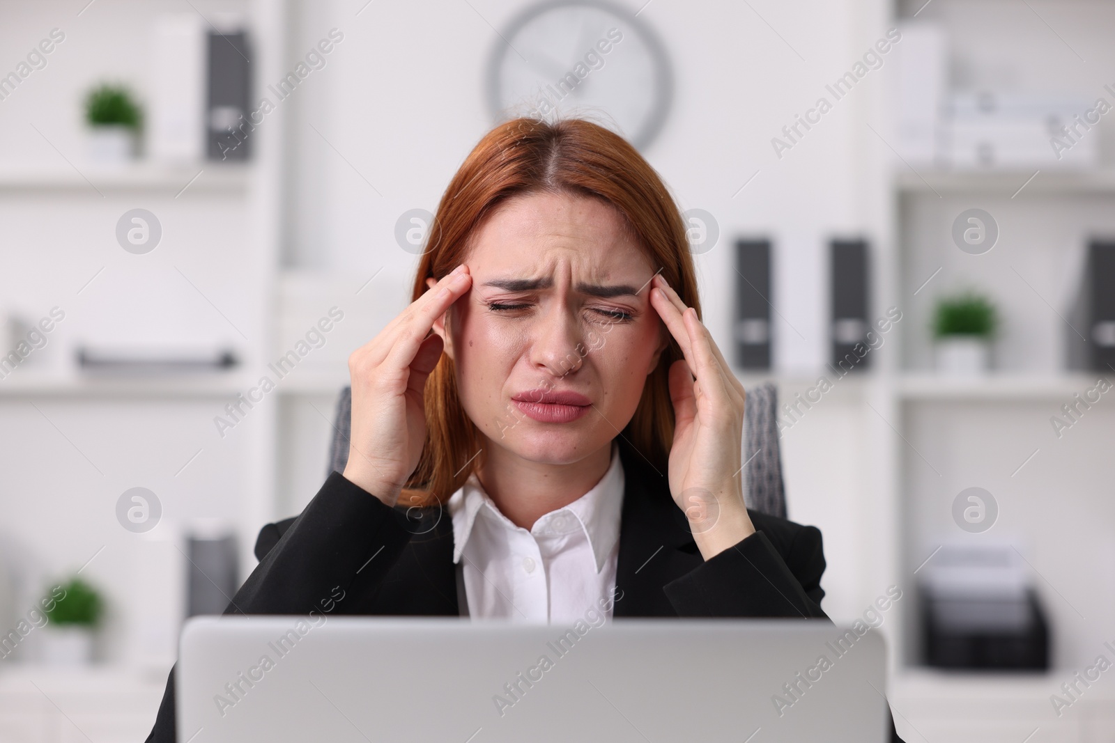 Photo of Woman suffering from headache at workplace in office