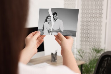Image of Divorce and breakup. Woman holding partsripped black and white photo at home, closeup