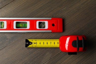 Photo of Building level and tape measure on wooden table, top view