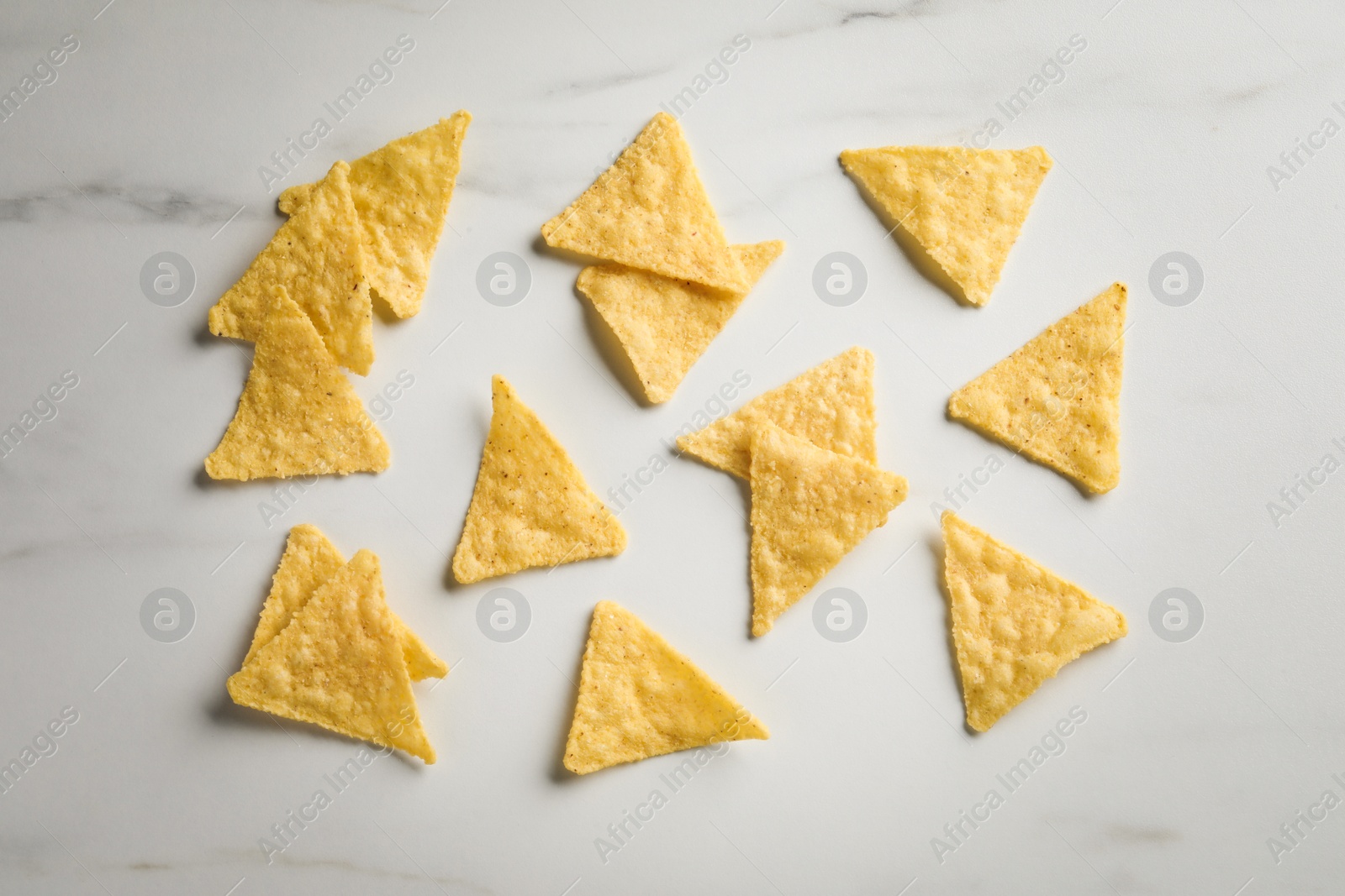 Photo of Flat lay composition of tasty tortilla chips (nachos) on white table