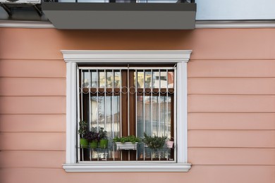 Beautiful window with grills and potted plants in building outdoors