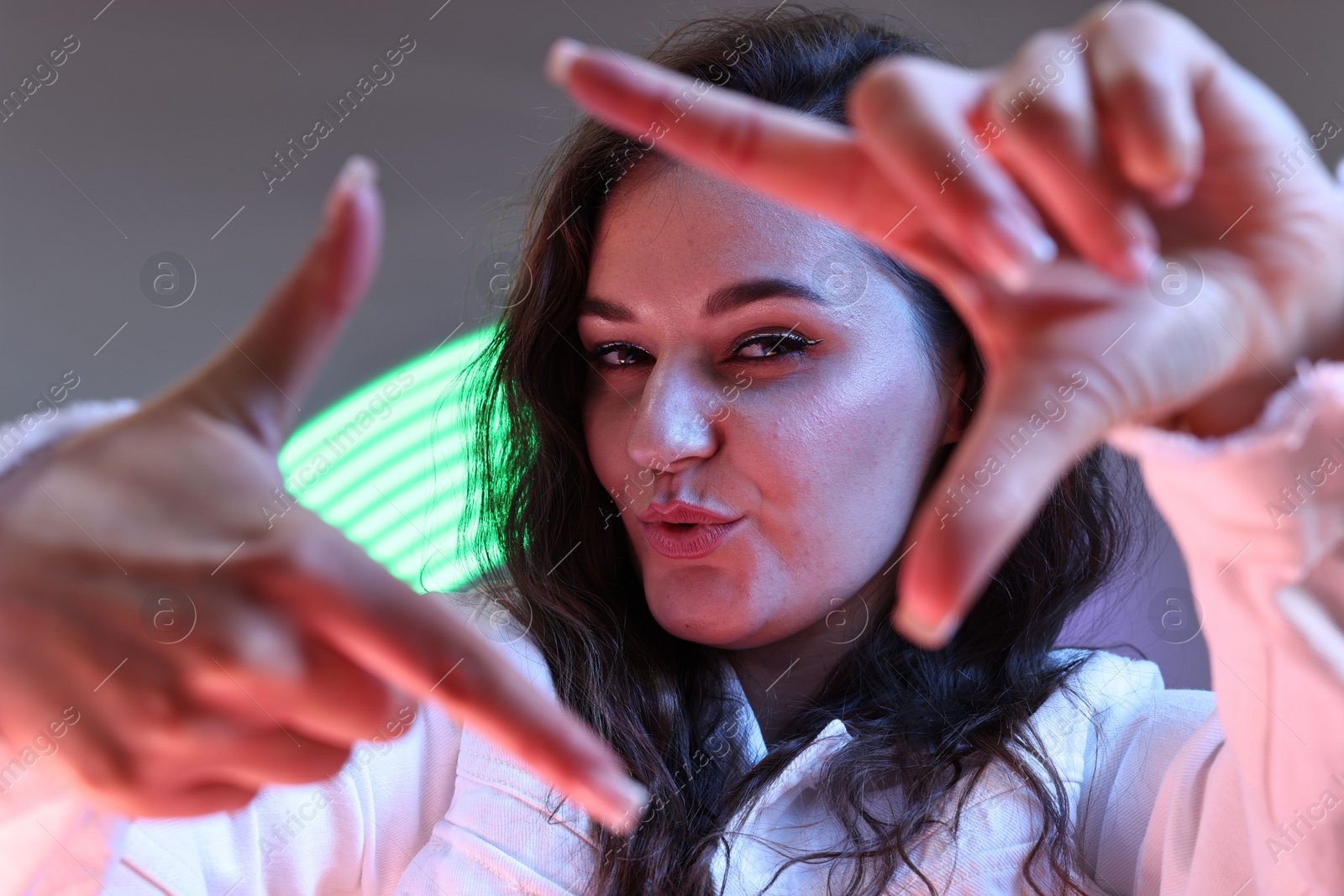 Photo of Portrait of beautiful young woman on color background with neon lights