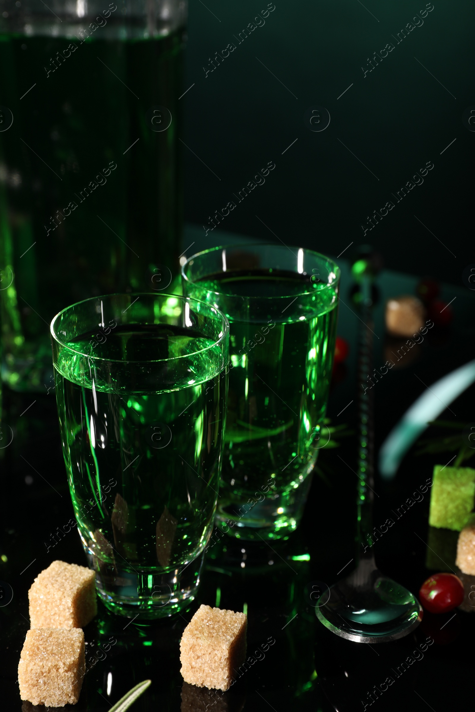 Photo of Absinthe in shot glasses brown sugar and spoon on mirror table. Alcoholic drink