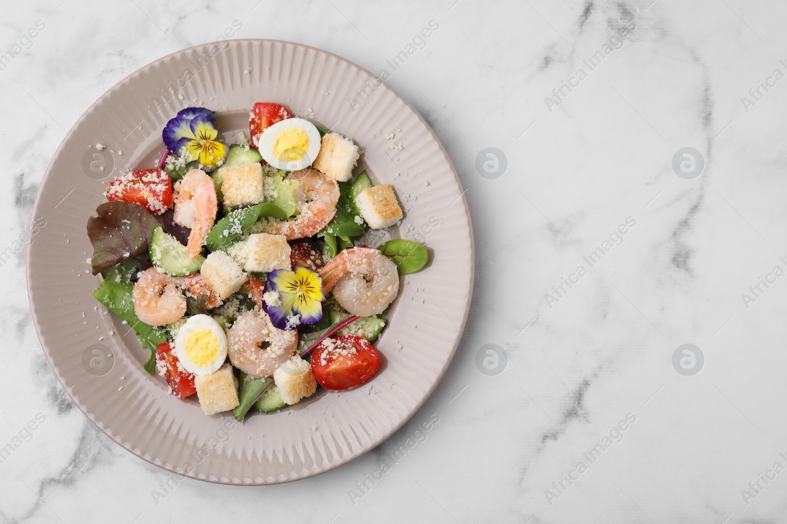 Photo of Delicious Caesar salad with shrimps on white marble table, top view. Space for text