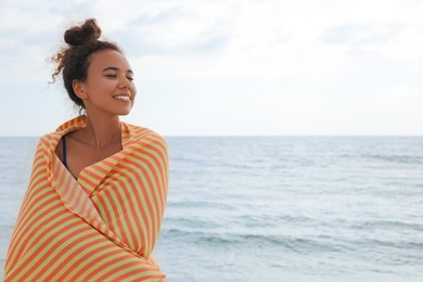 Photo of Beautiful African American woman with beach towel near sea