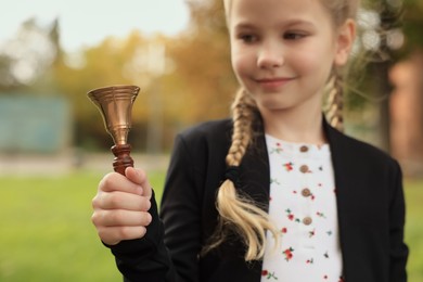 Photo of Pupil with school bell outdoors, focus on hand