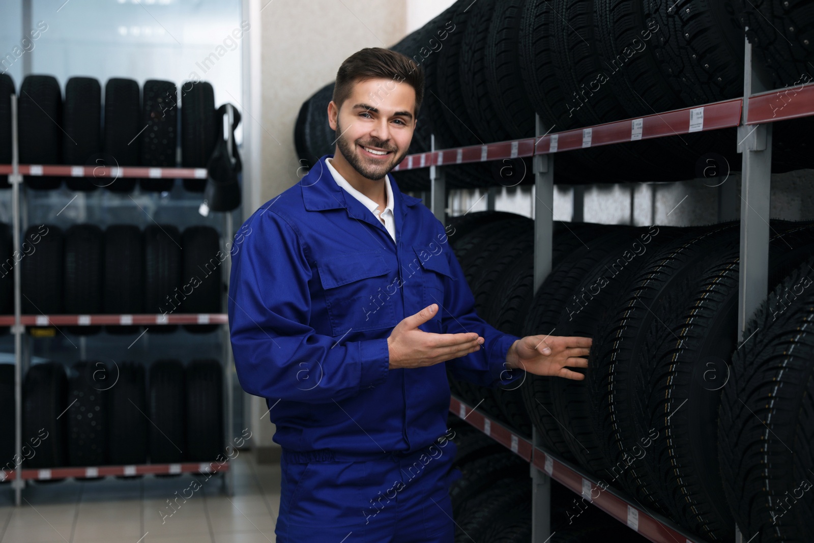 Photo of Male mechanic near rack with tires in auto store