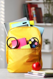 Photo of Yellow backpack and different school stationery on table indoors