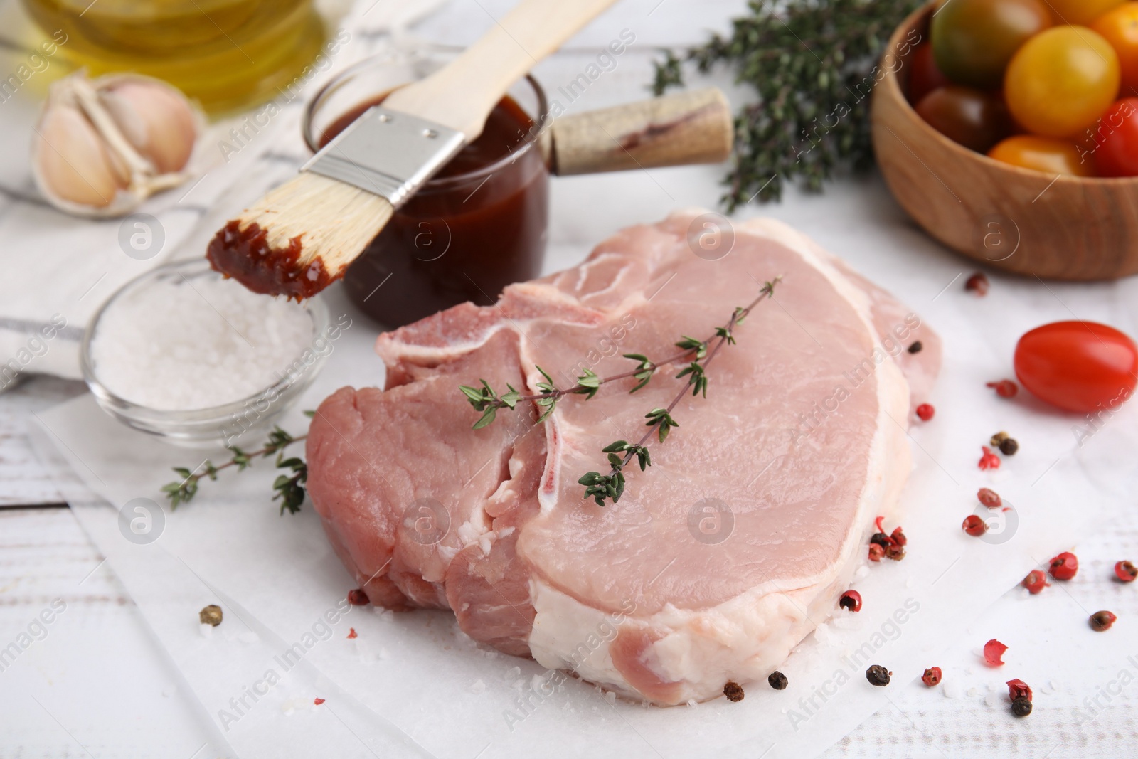 Photo of Raw meat, thyme, spices, basting brush and marinade on rustic wooden table, closeup