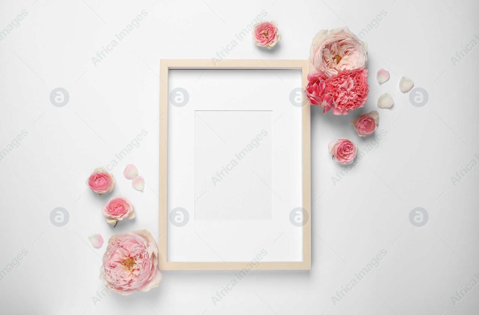 Photo of Empty photo frame and beautiful flowers on white background, flat lay. Space for design