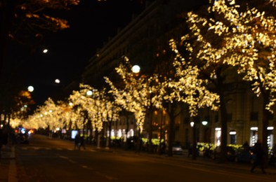 Photo of Blurred view of street with beautiful lights on trees at night