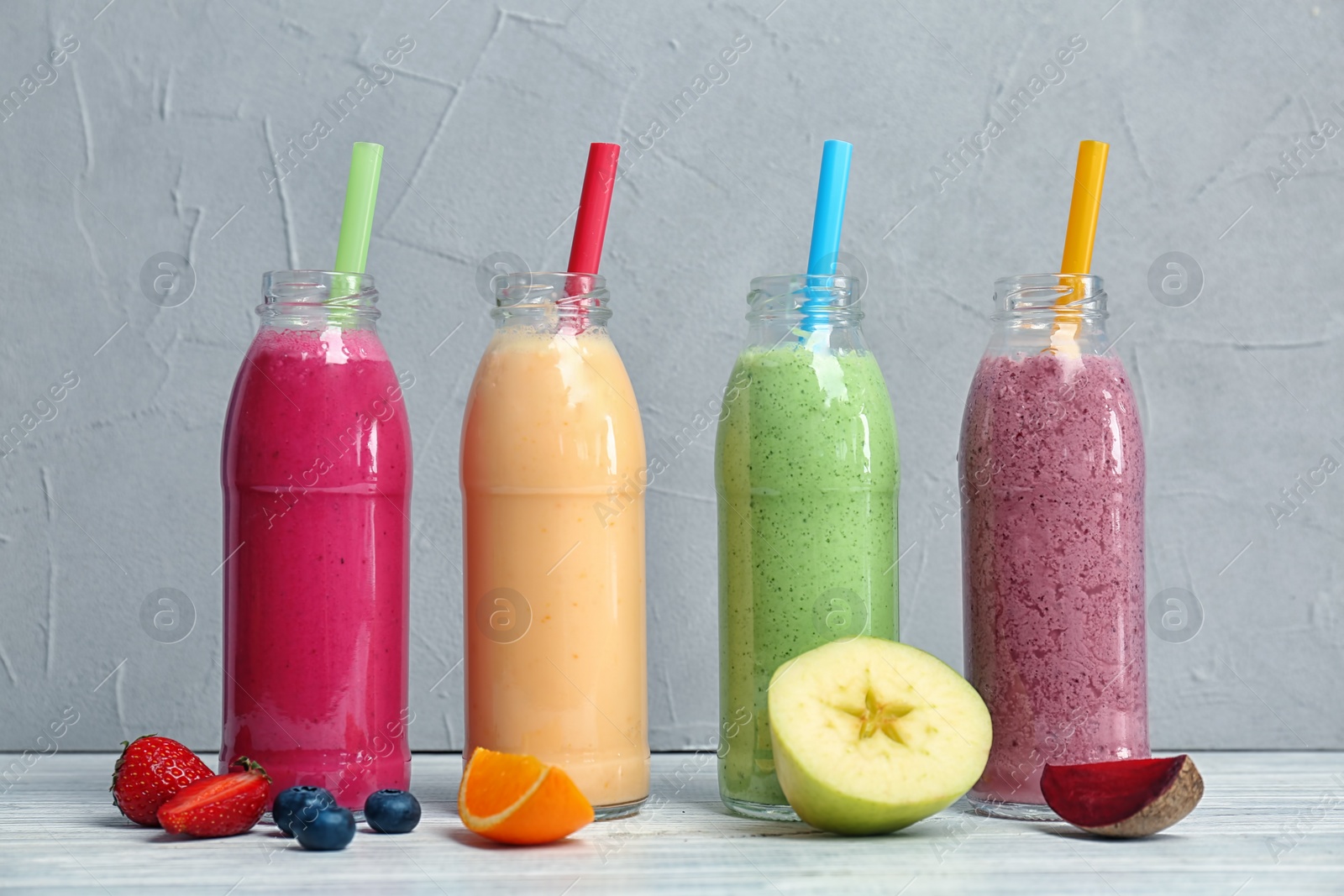 Photo of Bottles with healthy detox smoothies and ingredients on table