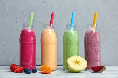 Photo of Bottles with healthy detox smoothies and ingredients on table