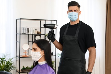 Photo of Professional stylist working with client in salon. Hairdressing services during Coronavirus quarantine