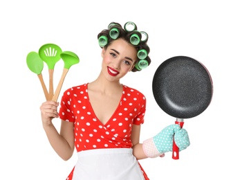Funny young housewife with frying pan and cooking utensils on white background