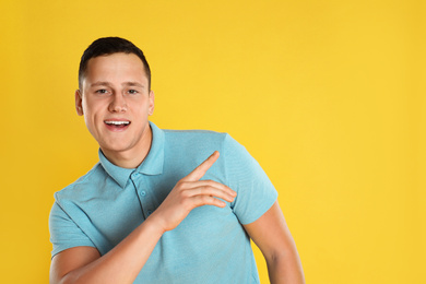 Photo of Happy handsome young man on yellow background. Space for text