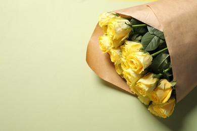 Beautiful bouquet of yellow roses on light green background, above view. Space for text
