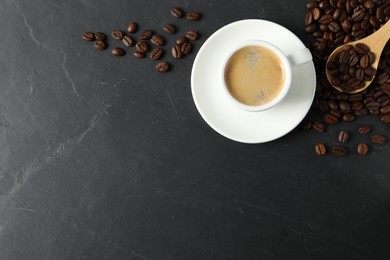 Photo of Cup of aromatic coffee and beans on black table, flat lay. Space for text