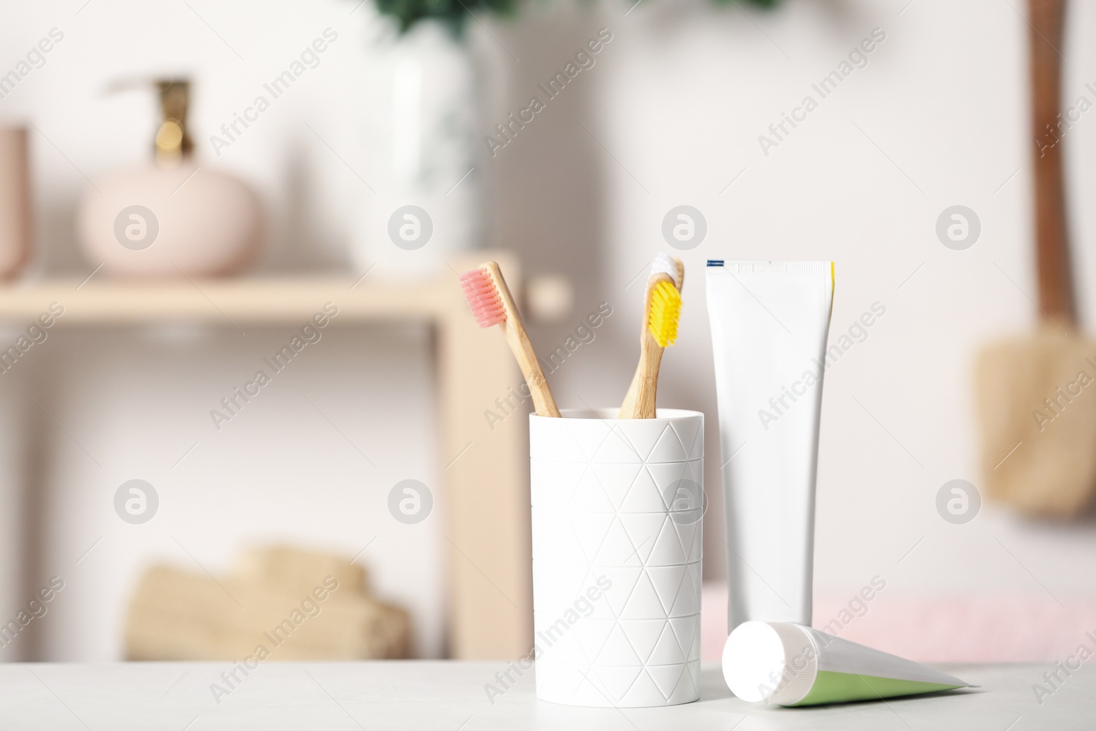 Photo of Bamboo toothbrushes and paste on light table indoors. Space for text