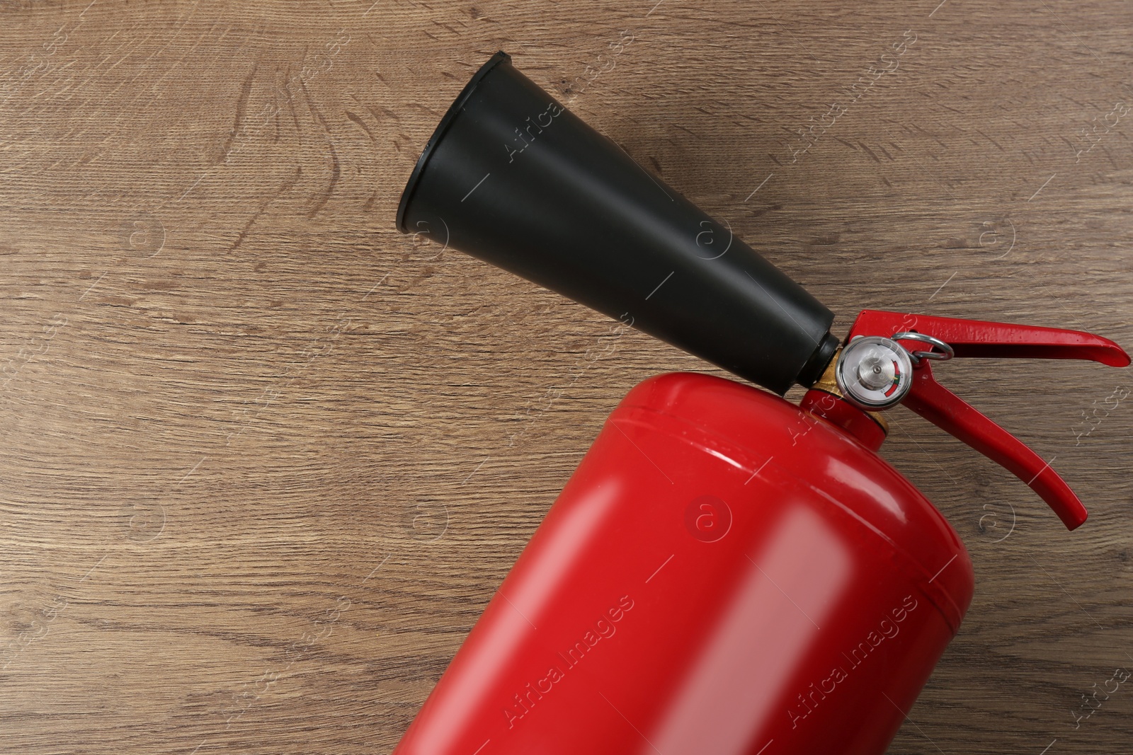 Photo of Fire extinguisher on wooden background, top view