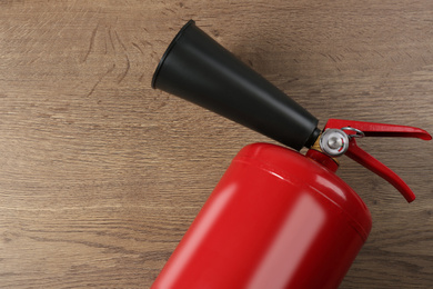 Fire extinguisher on wooden background, top view