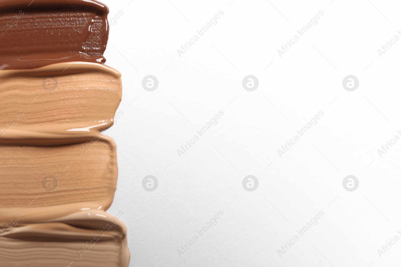 Photo of Samples of skin foundation on white background, top view. Space for text