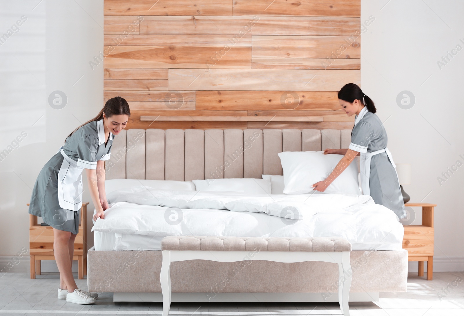 Photo of Young chambermaids making bed in hotel room