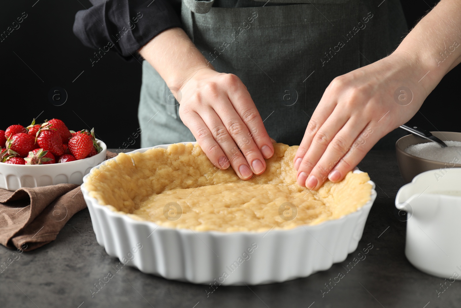 Photo of Shortcrust pastry. Woman making pie at grey table, closeup