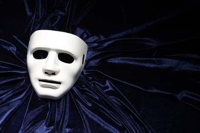 Theater arts. White mask on blue fabric, top view. Space for text