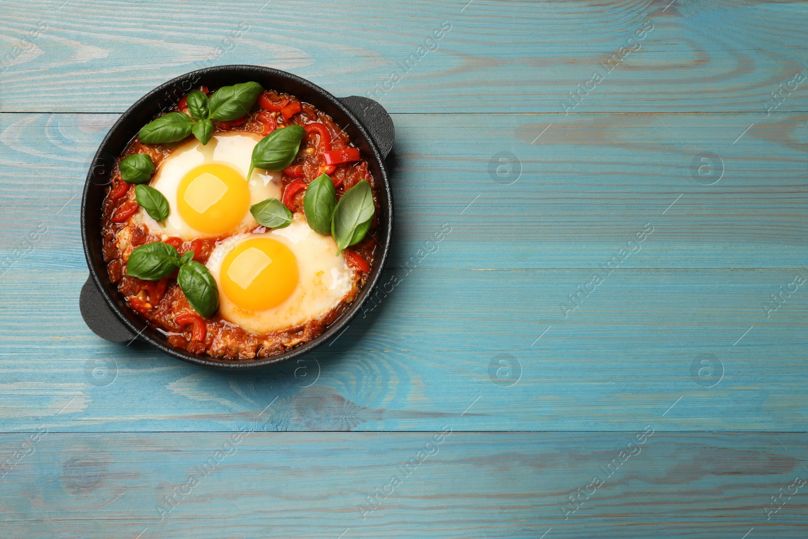 Photo of Delicious Shakshuka on light blue wooden table, top view. Space for text